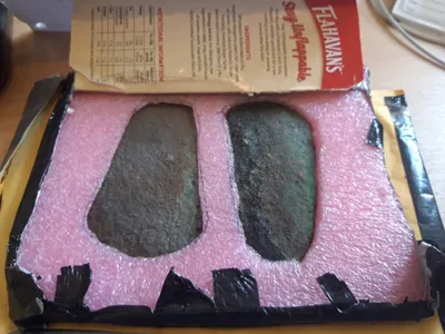 The anonymous sender secured the artifacts in foam cut-outs inside a cardboard flapjack box.