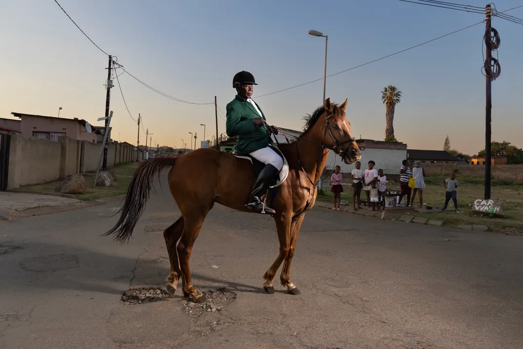 Enos Mafokate proudly wears his South African show jumping jacket on a ride through the streets of Soweto.