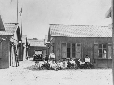 Athletes sit in front of a cabin in the Olympic Village at the 1924 Summer Olympics in Paris, France