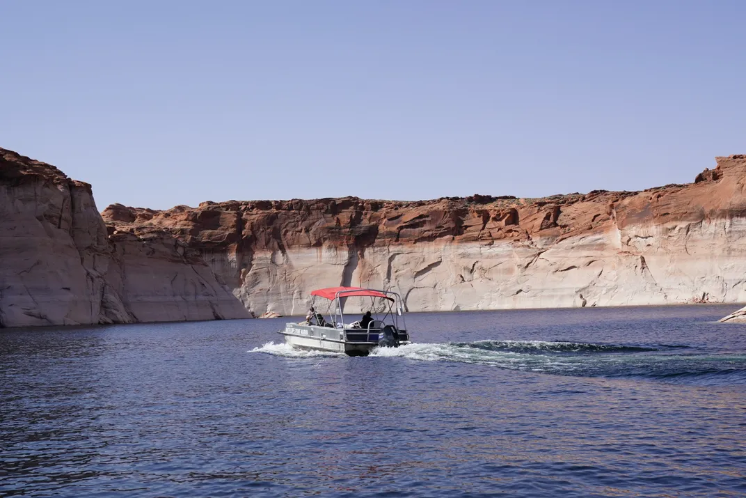 A boat in Lake Powell with a rocky wall in the background