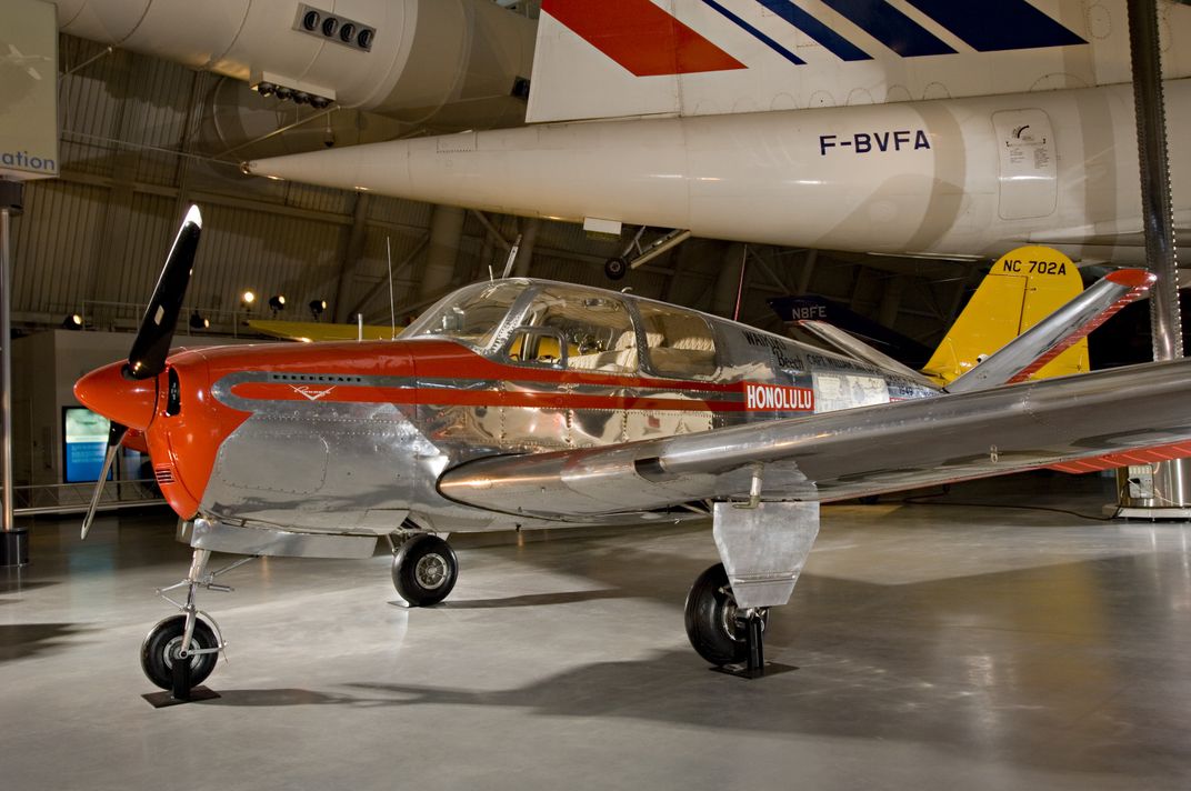 an antique red and silver airplane sits in a hanger