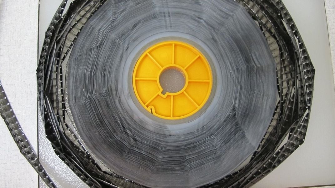 Yellow reel with black, decaying film on white background